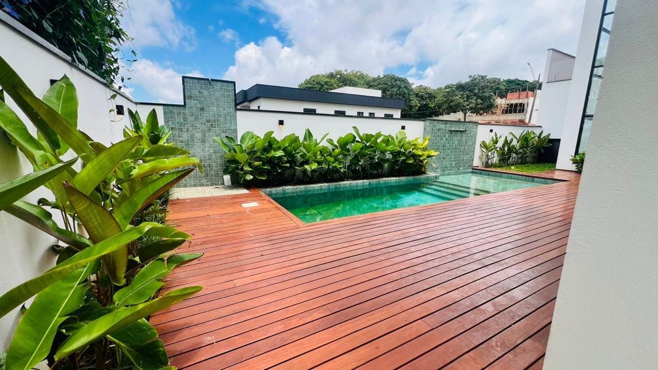 Piscina com deck de madeira e parede verde
